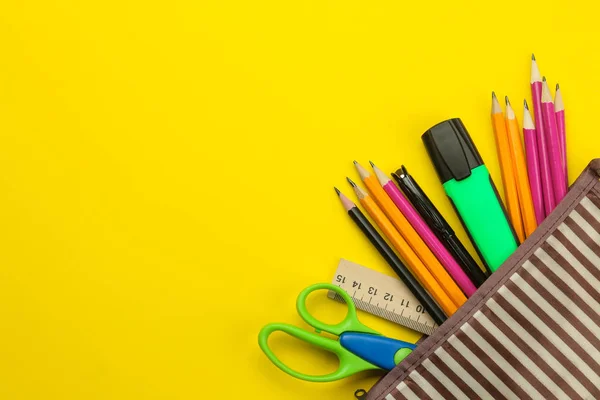 Color pencils in a school pencil case on a bright paper yellow background. Office tools. education. top view.