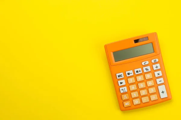 Parlak bir kağıt sarı arka planda turuncu hesap makinesi. Ofis malzemeleri. Eğitim. geri okula. üst görünüm. metin için yer.