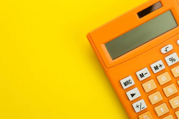 Parlak bir kağıt sarı arka planda turuncu hesap makinesi. Ofis malzemeleri. Eğitim. geri okula. üst görünüm. metin için yer.