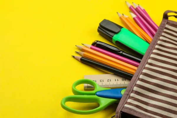 Color pencils in a school pencil case on a bright paper yellow background. Office tools. education.