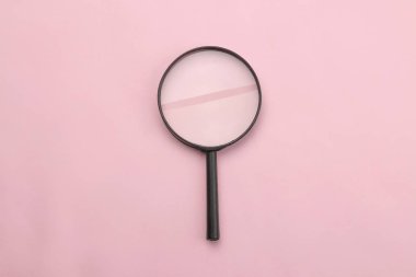 Parlak pembe Kağıt arka planda büyüteç. Ofis malzemeleri. Eğitim. geri okula. üst görünüm.