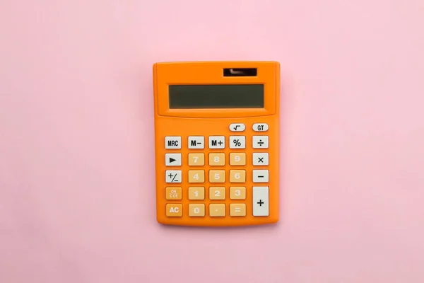 Parlak bir kağıt pembe arka planda turuncu hesap makinesi. Ofis malzemeleri. Eğitim. geri okula. üst görünüm.