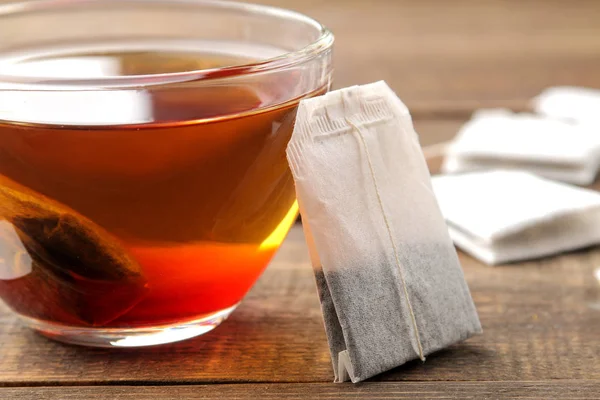 Kahverengi Ahşap Arka Plan Üzerinde Bir Cam Fincan Çay Poşeti — Stok fotoğraf