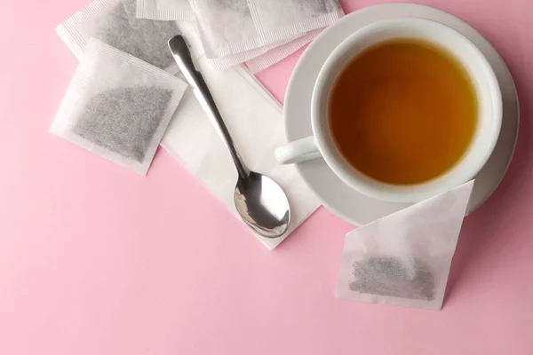 Tea bag pyramid and cup with tea on a delicate pink background. to make tea.