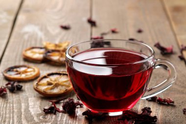 Ebegümeci kırmızı çay cam bardak kahverengi ahşap bir masa üzerinde. Isınma bir içecek. sonbahar veya kış içeceği