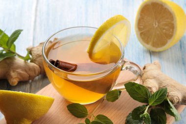 Kahverengi ahşap bir masada cam bardak zencefil ve nane ile limon ve tarçın sopa ile Çay. Isınma bir içecek. Sonbahar veya kış içeceği.