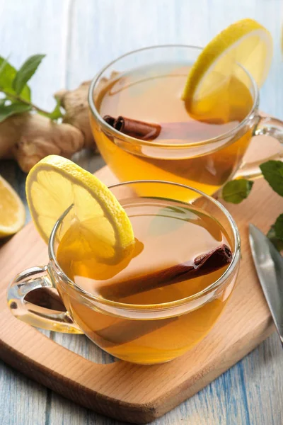 Tea with lemon and a cinnamon stick with ginger and mint in glass cups on a brown wooden table. a warming drink. Autumn or winter drink.