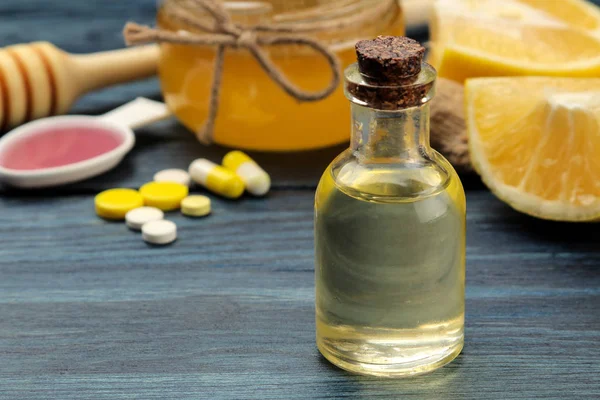 Medicines, pills, cough syrup, thermometer and folk remedies for the treatment of influenza and the common cold on a blue wooden table.