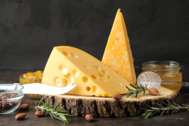 Koyu bir arka plan üzerinde bal, biberiye ve mendal ile lezzetli mermer peynir ve Maasdam peynir dilimleri