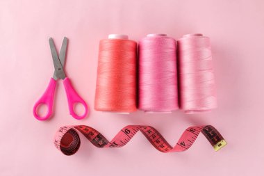 Dikiş ve iğne işleri için aksesuarlar. Parlak pembe bir arka plan üzerinde dikiş santimetre ve iplik makaraları