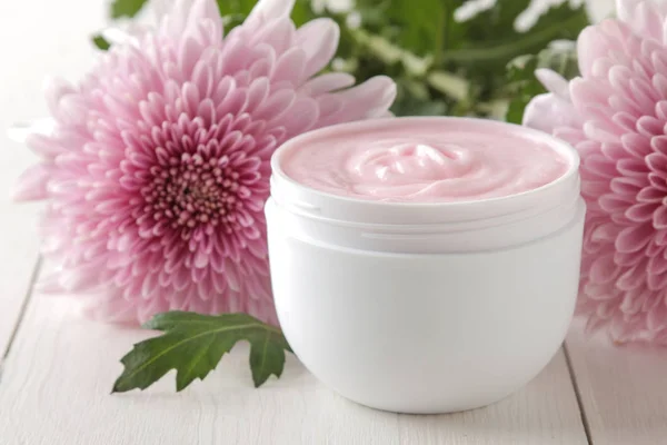 stock image Cream. cosmetics for face and body. Pink cream and flower in a white jar on a white wooden table