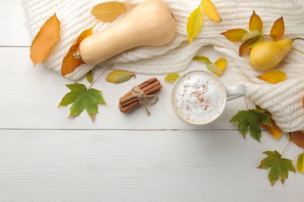 Hot autumn drink, coffee or cocoa, with yellow leaves and decorative pumpkins on a white wooden table. autumn composition. top view.