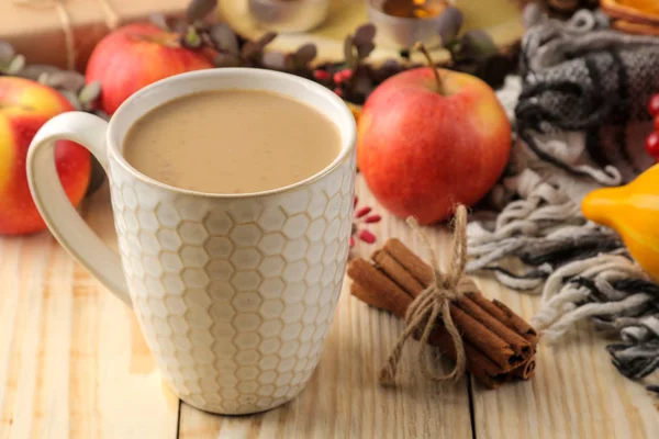 Hot autumn drink, coffee or cocoa, with yellow leaves and decorative pumpkins, acorns and apples on a natural wooden table. autumn composition.