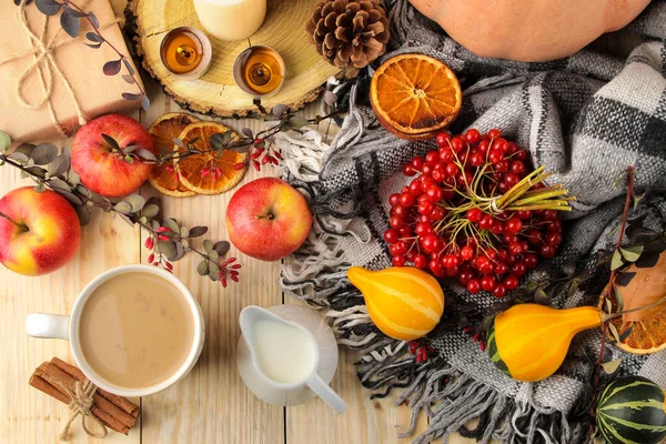 Hot autumn drink, coffee or cocoa, with yellow leaves and decorative pumpkins, acorns and apples on a natural wooden table. autumn composition. top view.