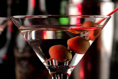 Martini. Bar tezgahındaki barda koyu bir arka plan üzerinde bir bardak zeytin ile alkollü içecek martini. bar envanteri. Kokteyl