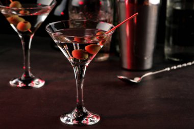 Martini. Bar tezgahındaki barda koyu bir arka plan üzerinde bir bardak zeytin ile alkollü içecek martini. bar envanteri. Kokteyl