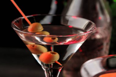 Martini. Bar tezgahındaki barda koyu bir arka plan üzerinde bir bardak zeytin ile alkollü içecek martini. bar envanteri. Kokteyl