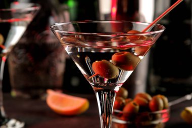 Martini. Bar tezgahındaki barda koyu bir arka plan üzerinde bir bardak zeytin ile alkollü içecek martini. bar envanteri. Kokteyl