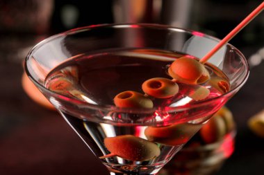 Martini. Bar tezgahındaki barda koyu bir arka plan üzerinde bir bardak zeytin ile alkollü içecek martini. bar envanteri. Kokteyl