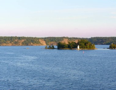 Akşam sakin denizde. Bir deniz feneri ile küçük bir ada. Baltık Denizi