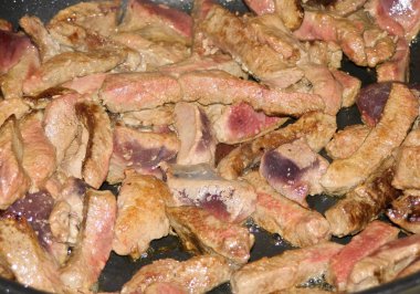 Bir tavada kızarmış domuz karaciğer parçaları