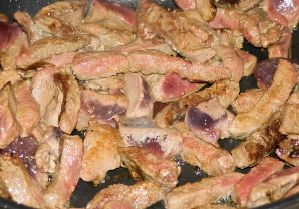 Bir tavada kızarmış domuz karaciğer parçaları