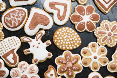 Beyaz ve Çikolata buzlanma-şeker siyah bir yüzey üzerinde Gingerbread çerezleri bir tavşan, çiçek, kalp, Anneannelerin, Paskalya yumurtaları, şeklinde kaplı