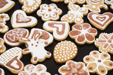 Beyaz ve Çikolata buzlanma-şeker siyah bir yüzey üzerinde Gingerbread çerezleri bir tavşan, çiçek, kalp, Anneannelerin, Paskalya yumurtaları, şeklinde kaplı