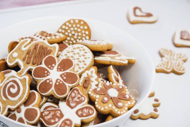 Gingerbread çerezleri bir Paskalya tavşanı, kelebek ve çiçek, şeklinde kaplı beyaz ve Çikolata buzlanma şeker, beyaz bir yüzey üzerinde beyaz bir tabak ile