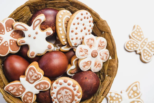 Çikolata ve Beyaz pudra şekeri ve yumurta beyaz bir yüzey üzerinde kahverengi bir sepet içinde Gingerbread çerezleri bir Paskalya tavşanı, çiçekler, kelebekler ve kalpleri şeklinde kaplı