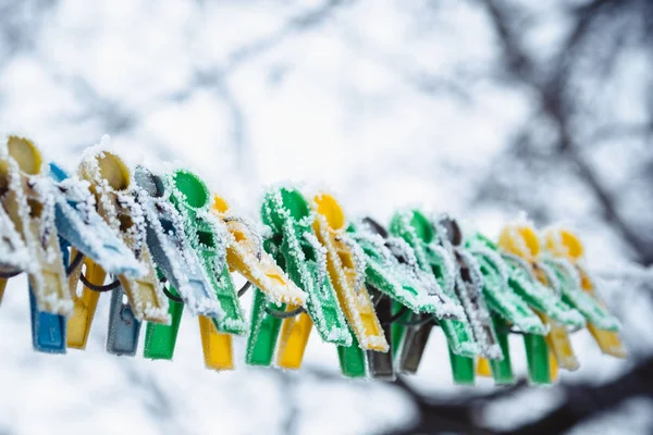 Clothesline üzerinde renkli clothespins kışın frost ile kaplıdır