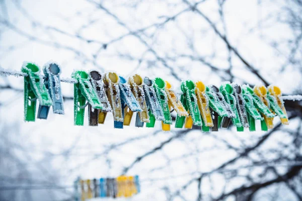 Clothesline üzerinde renkli clothespins kışın frost ile kaplıdır