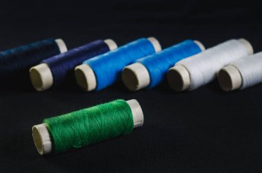 Siyah kumaş üzerine yeşil, mavi ve beyaz dizilerin makaralar