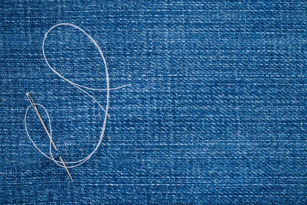 sewing needle and thread on denim closeup