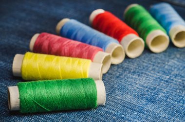 Renkli ipler, yarım daire denim kumaş üzerinde düzenlenen makaralar
