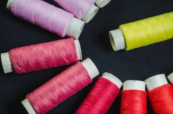Siyah kumaş üzerine pembe, kırmızı veya sarı dizilerin makaralar