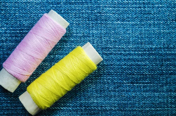 牛仔布上的黄色和粉红色螺纹线轴 — 图库照片