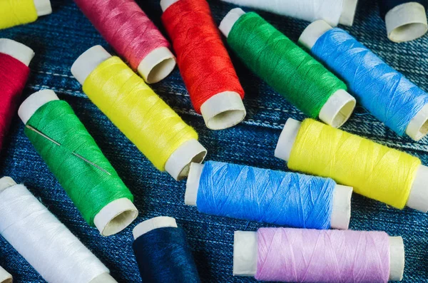 Spools of colored threads on denim fabric