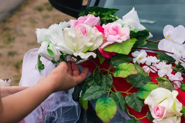 The process of decorating a wedding car with artificial flowers and drapery