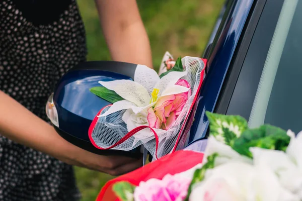 The process of decorating a wedding car with artificial flowers and drapery