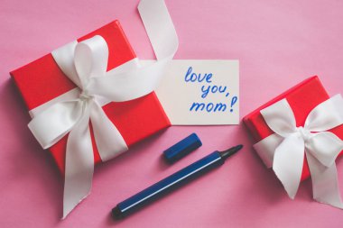 Kırmızı hediye kutusu bağlı beyaz bir şerit, işaretleri ve bir kart ile bir yazıt 