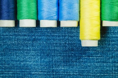 Mavi, sarı ve yeşil dikiş ipliği denim satırındaki kopya alanı ile düzenlenmiş makaralar