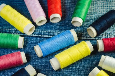 Mavi, beyaz, pembe, kırmızı ve yeşil dikiş ipliği mavi kot üzerinde makaralar