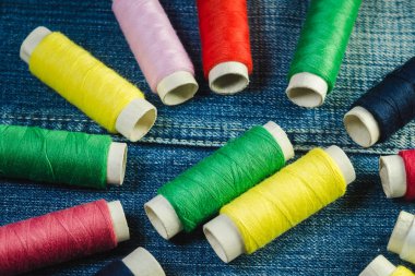 Mavi, beyaz, pembe, kırmızı ve yeşil dikiş ipliği kot üzerinde makaralar
