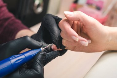 Siyah lateks eldiven manikürcü güzellik salonunda bir el ile elektrikli freze makinesi kullanarak tırnak eski Lehçe kaldırır.