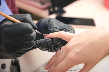 Siyah lateks eldiven manikürcü istemcinin çivi ile güzellik salonu bir renkli jel Lehçe kapsar.