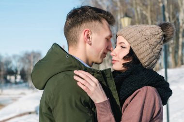 Parkta kış güneşli bir günde sarılma aşık genç çift yakın çekim