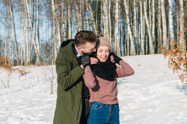 Güzel genç çift aşık yürür ve bir parkta bir açık güneşli kış gününde gülüyor.