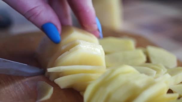 木製のカッティングボードのクローズアップ上のナイフで生のジャガイモを切断するプロセス — ストック動画