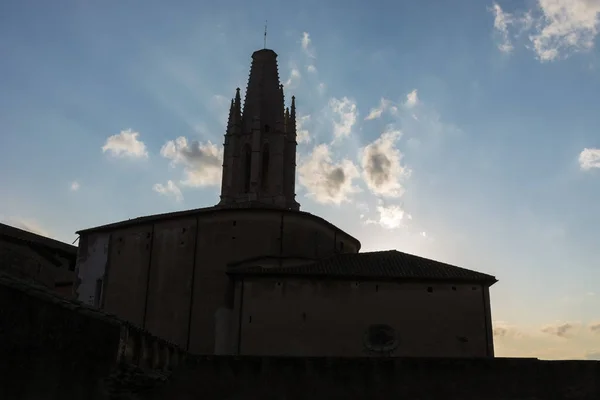 Mavi bir gökyüzü ve bazı bulutların arkasında akşam ile bir kulenin gölgeli bir siluet